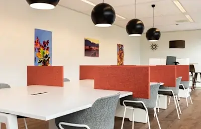 Helles Büro mit modernen Möbeln und einem großen Tisch, ideal zum Büro mieten. Kunstwerke an den Wänden ergänzen die Atmosphäre.