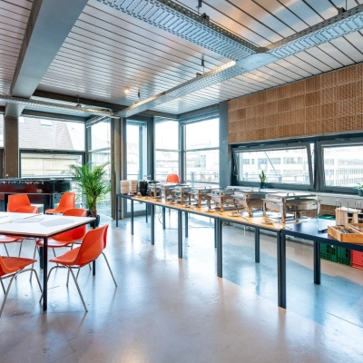 Heller Büroraum mit großen Fenstern in der Rudi-Dutschke-Straße 23, Berlin Kreuzberg, ideal zum Bürofläche mieten mit modernen orangen Stühlen und Tischgestaltung.