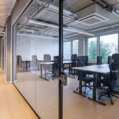 Moderner Büroraum mit Glaswänden in Berlin Mitte, ideal zum Büro mieten. Die Bürofläche bietet hochwertige Stühle und Tische, viel Tageslicht und eine klare, professionelle Umgebung.