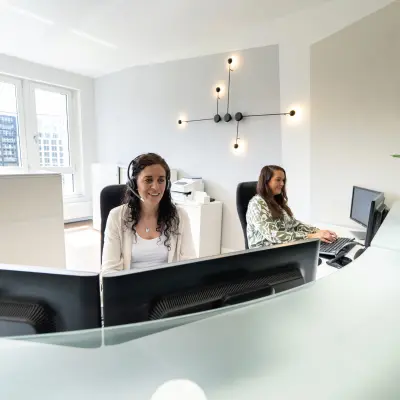 Helles Büro am Leipziger Platz 15, Berlin Mitte, mit stilvollen Büromöbeln und zwei arbeitenden Personen am Schreibtisch.