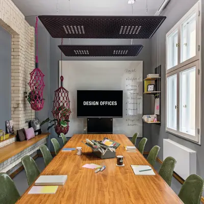 Moderner Konferenzraum in Berlin Mitte mit großem Holztisch und grünen Stühlen. Weiße Wände und Fenster bieten viel Tageslicht. Ideale Option für Büro mieten.