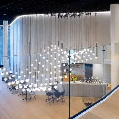 Modernes Büro in Frankfurt Bockenheim mit stilvollem Interieur und einem Cafébereich. Einladender Raum mit hängenden Leuchten und Glasgeländer. Perfekt für Büroraum mieten in Solmsstrasse 83.