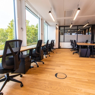 Moderner Büroraum in München Altstadt mit großen Fenstern, Holzfußboden und Schreibtischen; ideal zum Büro mieten und effizientes Arbeiten.