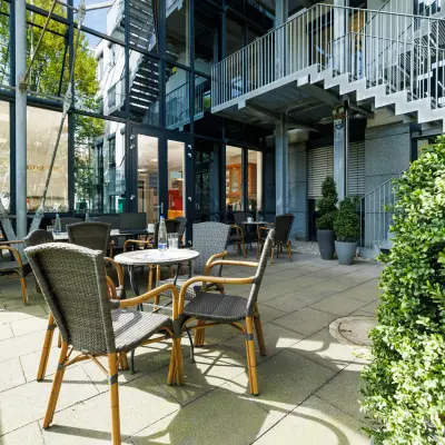 Moderner, heller Eingangsbereich mit Glastüren und Außenbestuhlung in München Laim. Ideal, um ein Büro zu mieten an der Landsberger Straße 155.