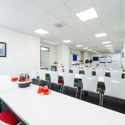 Moderne Konferenzraumfläche zur Miete in München Laim, Landsberger Straße 155, mit weißen Tischen und Stühlen, bereit für Meetings oder Seminare.