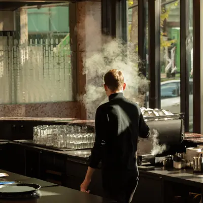 Sonnendurchfluteter Büroraum mit Panoramafenstern, modernem Espresso-Maschine, gestapelten Gläsern; ideal zum Büro mieten in Zürich City.