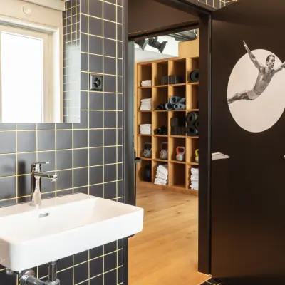 Moderner Büroraum mit dunkler Kachelwand, Waschbecken und offener Tür zur Fitness-Ecke; geeignet zum Bürofläche mieten im Zürich City, Talacker 41.