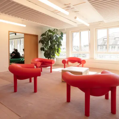 Helles Büro in Zürich City mit roten Sitzgelegenheiten und großen Fenstern, ideal zur Miete als Büroraum mit möbliertem Interieur.