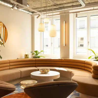 Heller, moderner Büroraum mit eleganter, geschwungener Ledercouch, runden Tischen und großen Fenstern in Zürich Enge. Ideal für Bürofläche mieten.