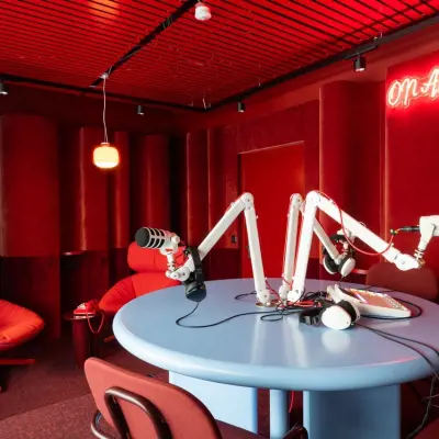 Modernes, rot gestaltetes Büro zur Miete mit Tisch und Mikrofonen in Zürich Enge, ideal für kreative Arbeitsumgebungen.