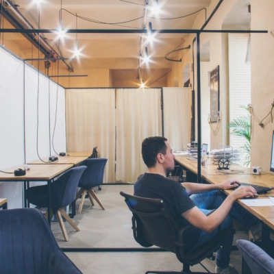 Spacious office to rent in Vienna's Alsergrund district at Zimmermanngasse 8. A person is working at a computer in a modern, open-plan workspace with wooden desks and comfortable seating.