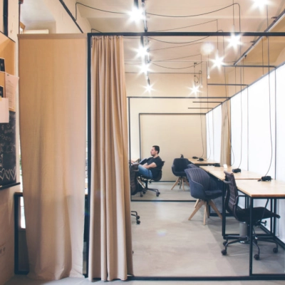 Modern office space with workstations and a person engaged in business activities at Zimmermanngasse 8, 1090 Vienna. Ideal office to rent with sleek design.
