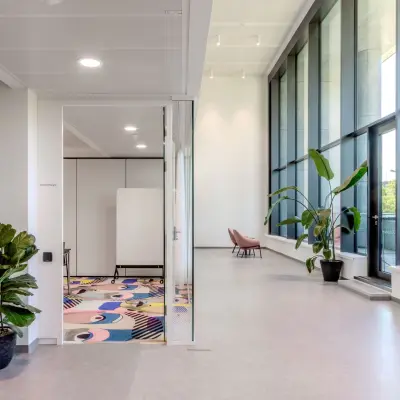 Bright office space at Siemensstraße 89, Vienna 1210, featuring large windows, some seating, and indoor plants, perfect for open floorplan office space rental.
