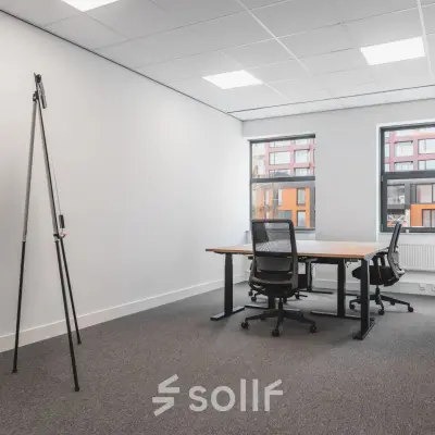 Furnished office space available for rent at Veluwezoom 15, Almere Stad, featuring desks and chairs set against large windows.