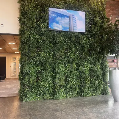 Bright lobby at Leidse Schouw 2, Alphen aan den Rijn with a lush green wall and TV screen, ideal for office space rental.