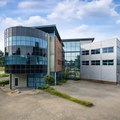 Modern office building located at Maanlander 43, Amersfoort Calveen, available for rent. Features a distinctive glass façade with ample parking space.