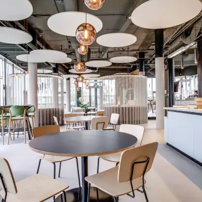 Modern office space with round tables, chairs, and circular ceiling lights, situated at Maanlander 47, ideal for office space rental in Amersfoort Calveen.