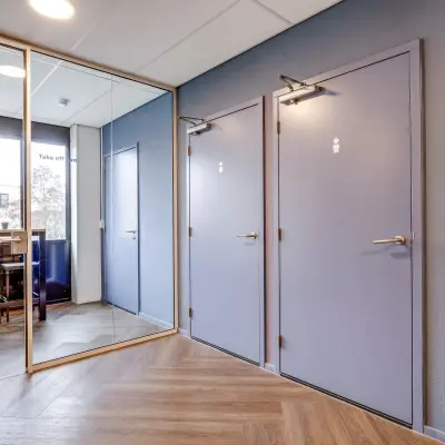 Modern office space rental at Maanlander 47 in Amersfoort Calveen with a mirrored hallway and doors leading to different areas.