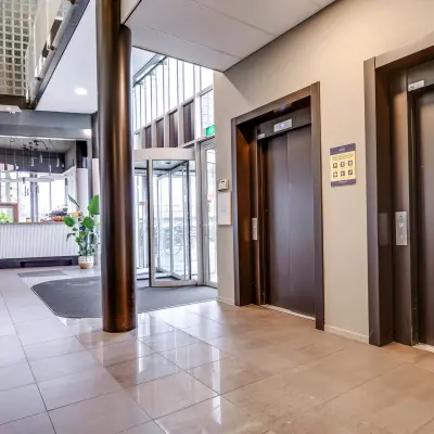 Bright office entrance at Maanlander 47, Amersfoort Calveen, showcasing elevators and a reception desk with office space rental opportunities.