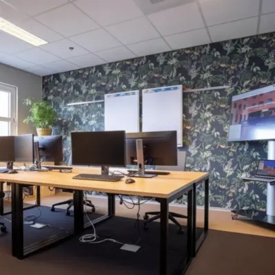 Stylish office space featuring multiple computer workstations, a large screen, and a plant, ideal for office space rental at Stationsplein 49, Amersfoort Centraal Station.