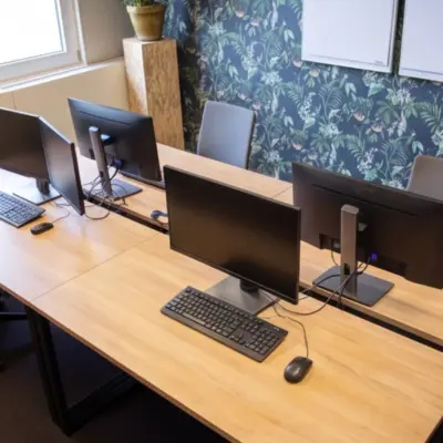 Comfortable office space rental at Amersfoort Centraal Station with wooden desks, computer monitors, and chairs for collaborative work.