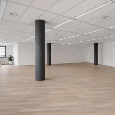 Spacious unfurnished office space with large windows and wooden flooring, ideal for office space rental in Amersfoort Centrum.
