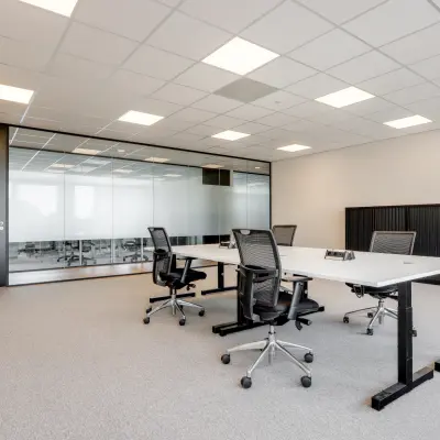 Furnished office space for rent at De Gondel 1, Amstelveen, featuring modern desks and chairs in a bright, carpeted room with glass partitions.
