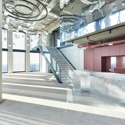 Spacious, modern interior at Amsterdam Amstel Business Park with sleek metallic decor, large windows, and an open stairway, ideal for office space rental. The space is bright with contemporary fixtures.