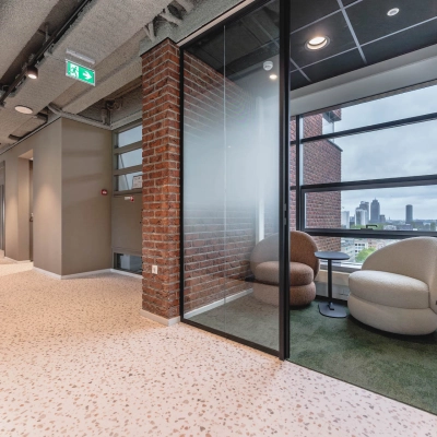 Modern office space with brick walls, glass partitions, and lounge seating at Joop Geesinkweg 201, Amsterdam Amstel Business Park, ideal for office space rental.