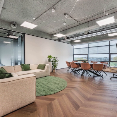 Modern furnished office space for rent at Amsterdam Amstel Business Park, featuring a meeting area with a table, chairs, and a seating section near the window at Joop Geesinkweg 201.