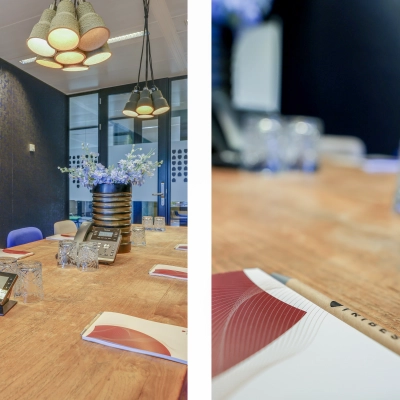 Modern conference room at Prins Bernhardplein 200, Amsterdam Amstel, featuring a wooden table, blue accent chairs, and pendant lighting, ideal for office space rental.