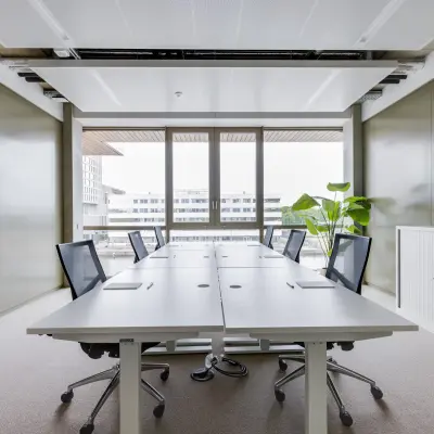 Modern office space in Amsterdam Amstel with large windows, conference tables, and sleek chairs. Ideal for office space rental.