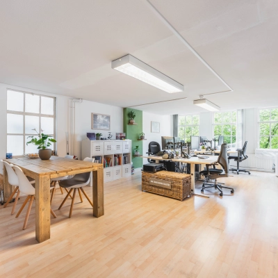 Furnished office space for rent at Herengracht 221, in the Amsterdam Canal Belt, featuring multiple workstations, natural light, and modern decor.