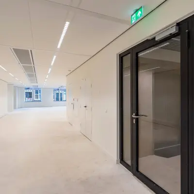 Empty office space available for rent at Herengracht 459-469, Amsterdam Canal Belt, featuring large windows and modern lighting.