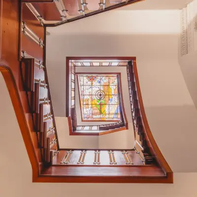 Spiral staircase with wooden railings and colorful stained glass window at Herengracht 582-584, Amsterdam Canal Belt, perfect for office space rental ambiance.