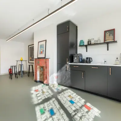 Bright interior space with modern black kitchenette, counter seating, and colorful floor patterns. Suitable for office space rental at Keizersgracht 261, Amsterdam Canal Belt.