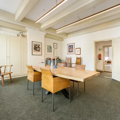 Furnished office space for rent at Keizersgracht 261, Amsterdam Canal Belt, featuring a spacious meeting area with a large wooden table and chairs, ideal for office space rental.