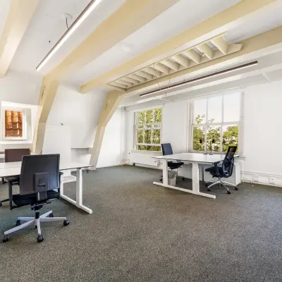 Bright office space rental at Keizersgracht 261, Amsterdam Canal Belt, featuring desks and chairs with natural light pouring in.