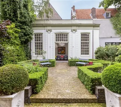 Exterior of office space rental at Keizersgracht 62-64 in Amsterdam Canal Belt, featuring a lush garden path leading to a historic building facade.