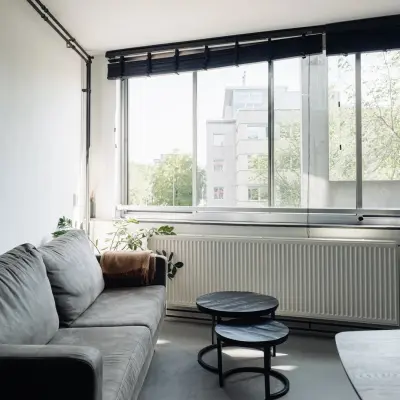 Bright office space with a cozy gray sofa, nested tables, and large windows at Weesperstraat 394-396, perfect for office space rental in Amsterdam Canal Belt.