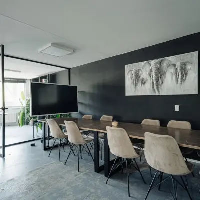 Modern office space with a large wooden table, chairs, and wall artwork at Weesperstraat 394-396, perfect for office space rental in Amsterdam Canal Belt.