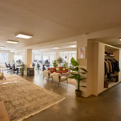Spacious office space with various workstations, a comfortable lounge area, and abundant natural light, perfect for office space rental in Amsterdam Center.
