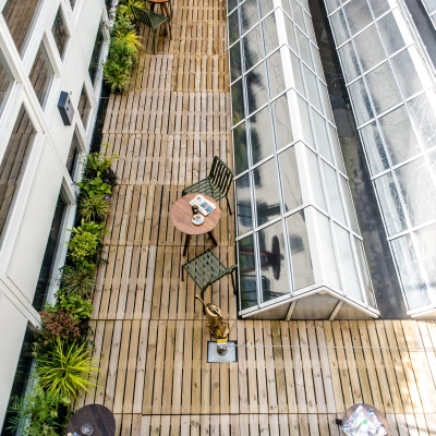 Rooftop terrace of the office located at Muiderstraat 1, Amsterdam Center. Features wooden decking, greenery, tables and chairs ideal for casual meetings or breaks. A unique spot for office space rental.