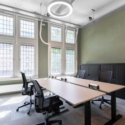 Bright and modern office space with large windows and stylish furniture, located at Nieuwezijds Voorburgwal 104-108, perfect for office space rental in Amsterdam Center.