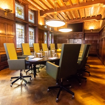 Elegant conference room with high-backed chairs around a long table, featuring wood-paneled walls and stained glass windows in Amsterdam Center.