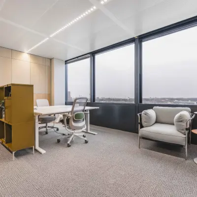Bright office space with large windows at Piet Heinkade 55, ideal for those seeking an office to rent in Amsterdam Center. Includes a desk, chairs, and storage unit.