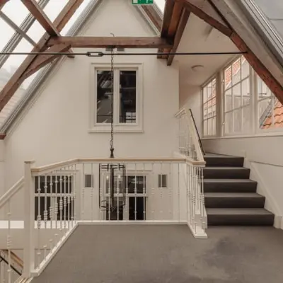 Interior of an office space at Prins Hendrikkade 14, Amsterdam Center, featuring large windows and exposed wooden beams, ideal for office space rental.