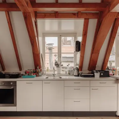 Bright kitchen area under exposed wooden beams with a modern counter setup at Prins Hendrikkade 14, ideal for breaks in an office space rental.