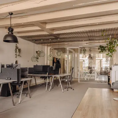Modern office space at Prins Hendrikkade 14, Amsterdam Center, featuring open desks with computers, chairs, and decorative plants, ideal for office space rental.