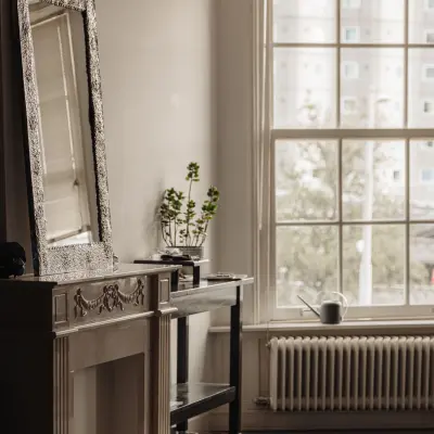 Interior view of an office space with a decorative fireplace, window, and a small table with a plant, located in Amsterdam Center.